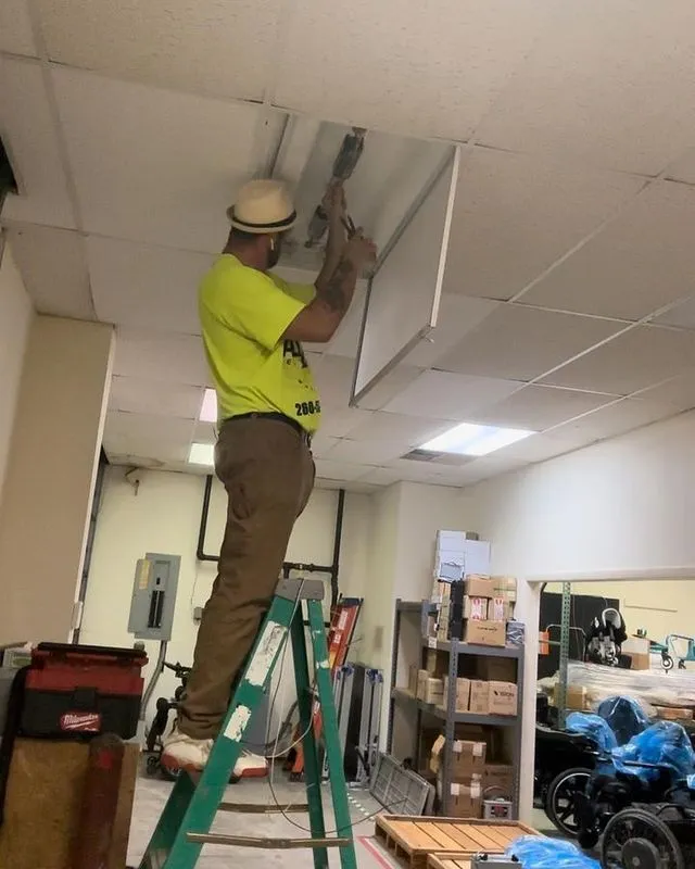 Electrician on a ladder working in a drop ceiling