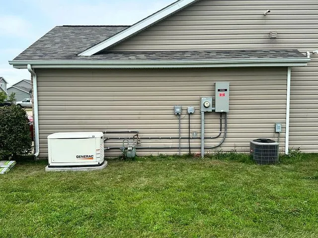 Generac standby generator set on a pad beside a house, with the transfer switch and meter on the wall