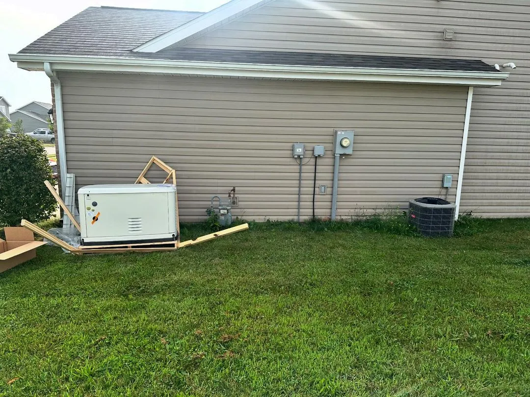 Standby generator installed next to the air conditioner on the side of a house