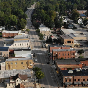 Aerial view of a small town intersection with brick buildings, tree-lined streets, and cars parked along the roads, highlighting local businesses including a trusted electrical contractor offering reliable electrician services in Angola.